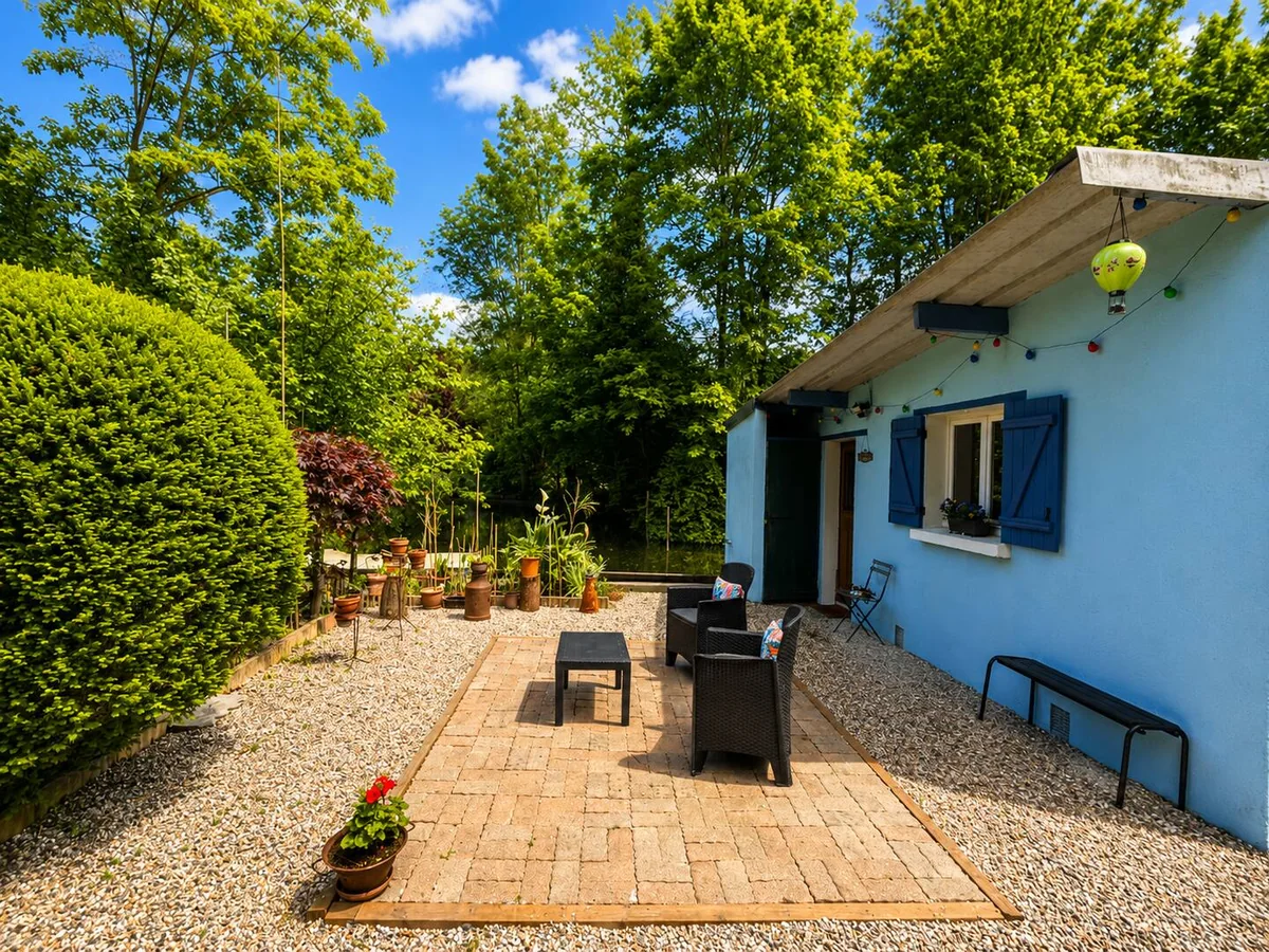 La terrasse pavée et le salon de jardin le long de la maison bleue